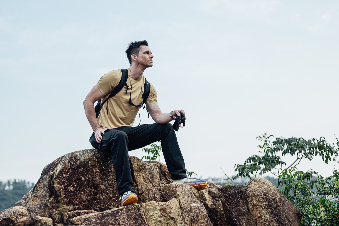 Sitting on a boulder with a camera in All Rounder Adventure.